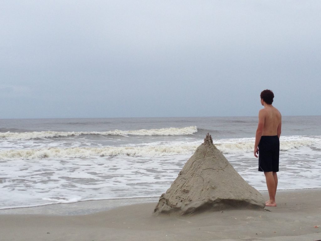 Boy by his sandcastle